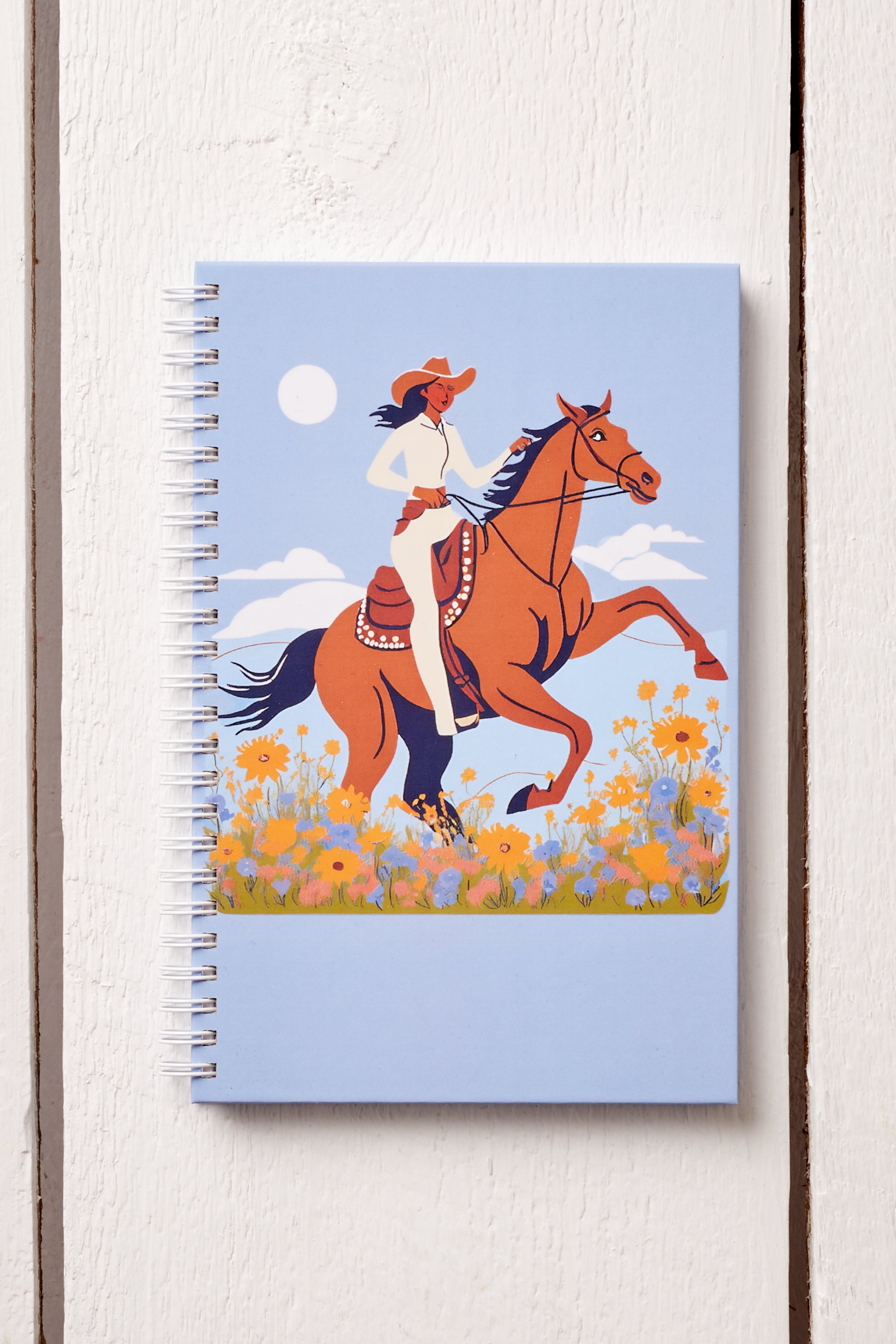 COWGIRL RIDING HORSE IN MEADOW HARDCOVER JOURNAL